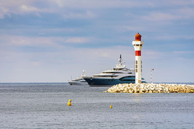 Lighthouse by sea against sky