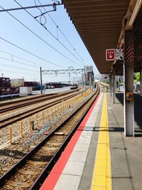 Railway tracks at railroad station against sky