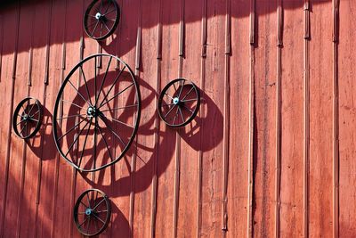 Antique wagon wheels mounted on side of red barn.