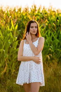 Portrait of young woman standing against plants