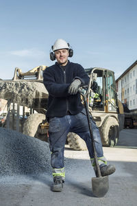 Full length portrait of confident worker standing at construction site