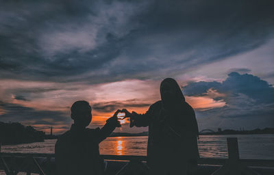 People photographing sea against sky during sunset