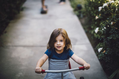 High angle view of cute girl riding bicycle on footpath