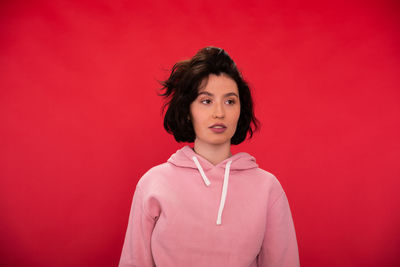 Portrait of beautiful young woman standing against red background