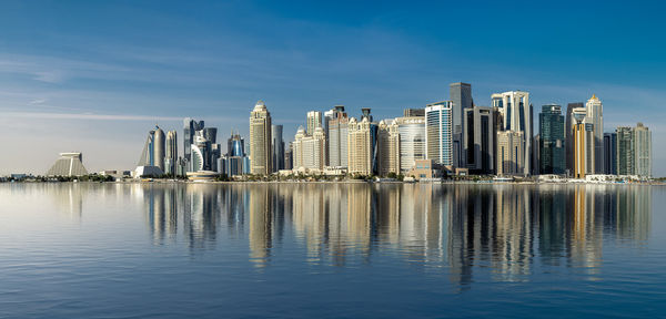Buildings by river against sky