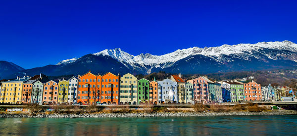 Scenic view of townscape by mountains against clear blue sky