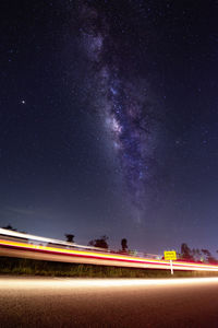 Light trails on road against sky at night