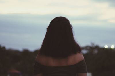 Rear view of woman standing against sky during sunset