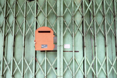 Close-up of mailbox on fence against wall