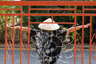 Rear view of mature woman wearing asian style conical hat while standing by gate