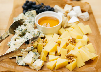 Cheese platter with blue cheese, honey and grapes on wooden table. big pile of cheeses.