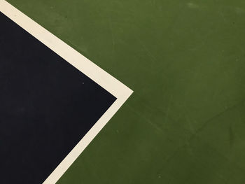 Dark blue and white triangle shape with the green surface at the right side of tennis indoor court