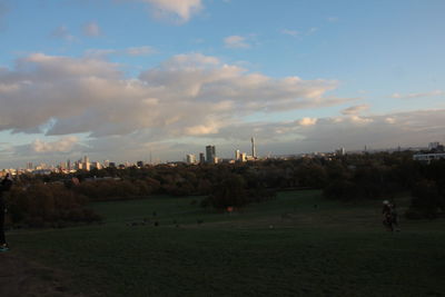 People by cityscape against sky