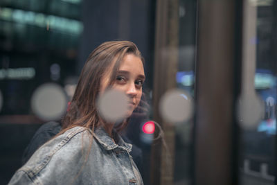 Portrait of young woman seen through glass window