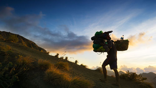 People on mountain against sky during sunset