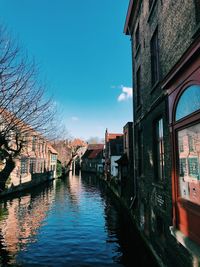 Canal amidst buildings against sky in city