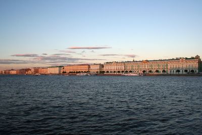 Sea by buildings against clear sky