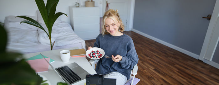 Portrait of smiling young woman using digital tablet while sitting on table