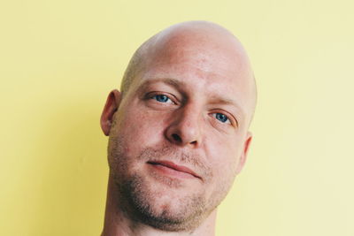 Close-up portrait of mid adult man against yellow background