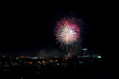 Firework display in city against sky at night