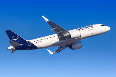 Low angle view of airplane flying against clear blue sky