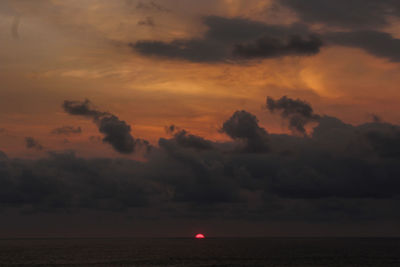 Scenic view of sea against dramatic sky during sunset