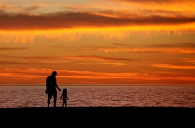 Silhouette of man standing on beach at sunset