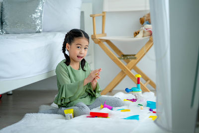 Portrait of boy sitting on bed at home