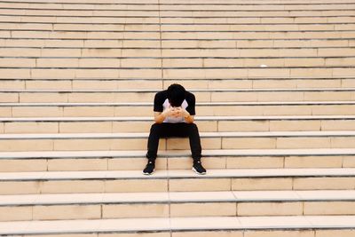 Full length of woman sitting on staircase against wall