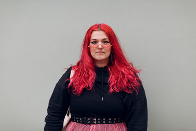 Portrait of beautiful young woman standing against wall