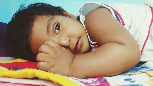 Portrait of cute baby girl lying on bed at home