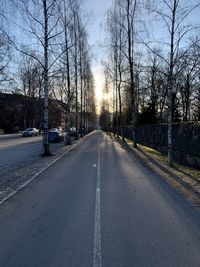 Road amidst bare trees in city