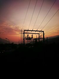 Silhouette of electricity pylon at sunset