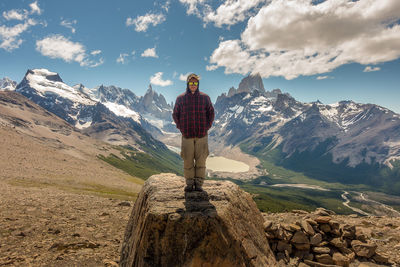 Rear view of man standing on mountain against sky