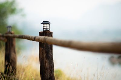 Close-up of wooden post on field against sky