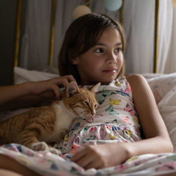 Smiling girl with cat on bed at home