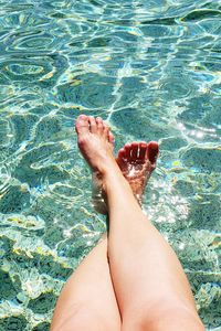 Low section of person relaxing in swimming pool