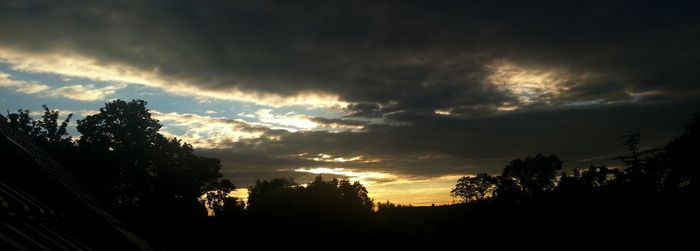 Silhouette of trees against cloudy sky