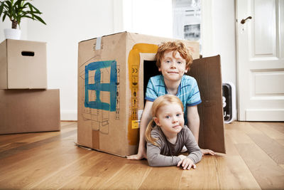 Brother and sister looking out of a cardboard box in new apartment