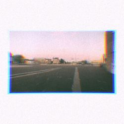 Road by buildings against sky seen through window