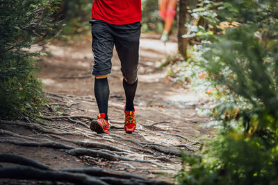 Low section of man walking on rock in forest