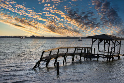 Silhouette pier over sea against sky during sunset