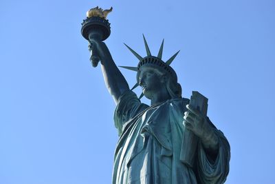 Low angle view of statue of liberty against blue sky