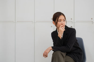 Portrait of young businesswoman standing against wall