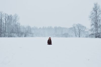 Man on snow covered trees against sky