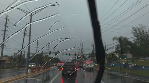 Cars on road against sky during rainy season