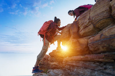 People on rock formation against sky