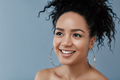Portrait of young woman with curly hair against blue background