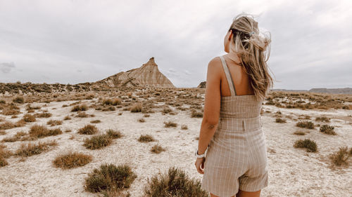 Rear view of woman standing at desert against sky