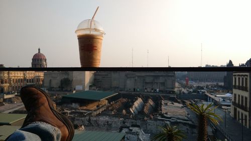 Low section of man by building against sky in city